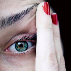 Frau fasst sich ans Auge: Mit bestimmten Symptomen sollte man schnell zum Augenarzt