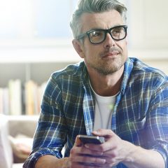 Vitamin B12 Depressionsrisiko: Mann mittleren Alters und mit Brille im Wohnzimmer