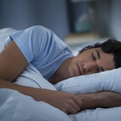 Junger Mann schläft auf der Seite mit Kopfkissen